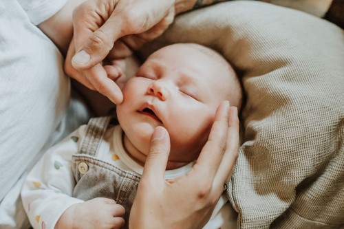 Hände über dem Kopf von einem schlafenden Baby.