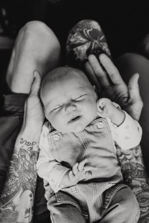 Ein kleines Baby auf dem Schoß von einem Mann.