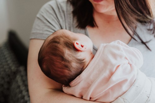 Ein kleines Baby auf dem Arm einer Frau.
