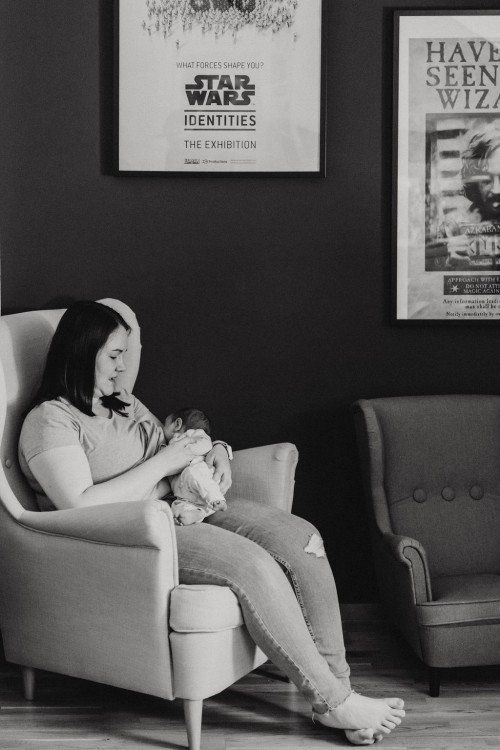 Eine Frau sitzt im Sessel und stillt ein kleines Baby.