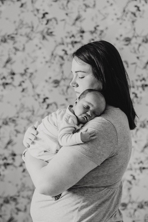Ein kleines Baby schläft bei einer Frau auf dem Arm.