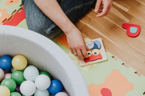 Eine Frau sitzt auf dem Boden und spielt mit Baby Spielzeug.