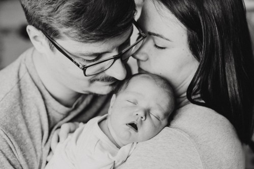 Eine Frau und ein Mann kuscheln mit einem Baby.