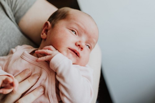 Ein kleines Baby auf dem Arm einer Frau.