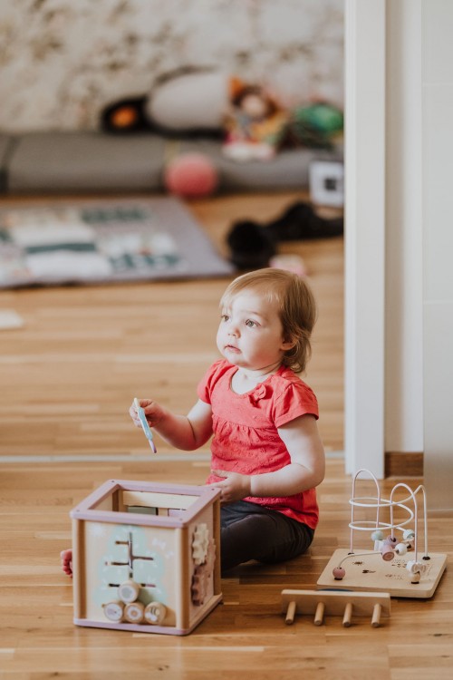 Ein kleines Mädchen sitzt auf dem Boden und spielt.