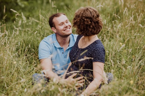 Ein Mann und eine Frau sitzen mitten auf der Wiese und schauen sich an
