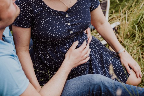 Ein Mann hält seine Hände am Bauch seiner Frau