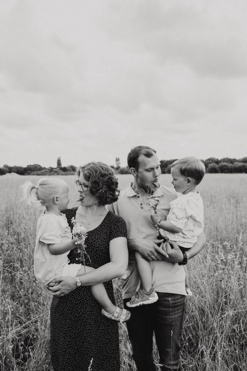 Eine Frau und ein Mann halten kleine Kinder im Arm und zeigen den die Zunge.