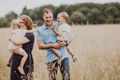 Eine Frau und ein Mann halten kleine Kinder im Arm.