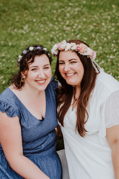 Zwei Frauen mit Blumenkranz schauen lächelnd in die Kamera.
