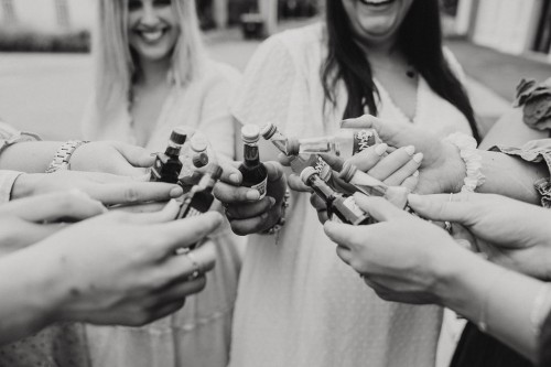 Eine Gruppe stoßt mit kleinen Fläschchen an.