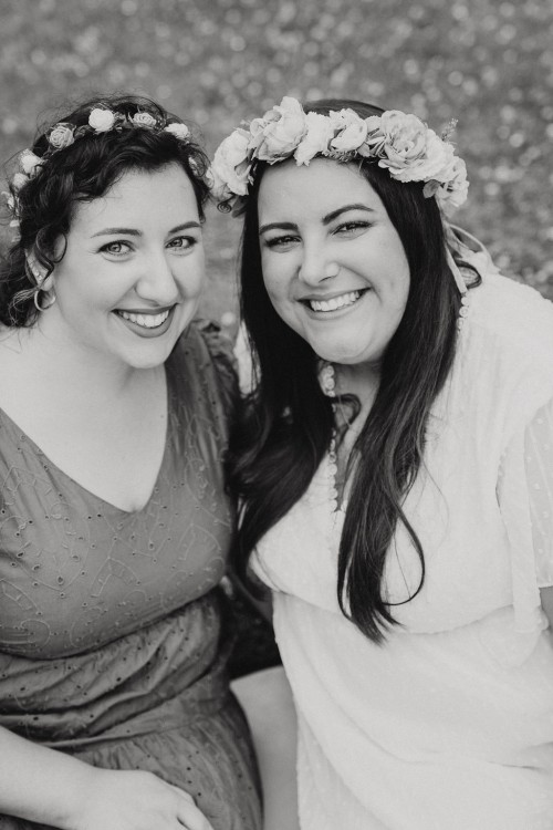 Zwei Frauen mit Blumenkranz schauen lächelnd in die Kamera.