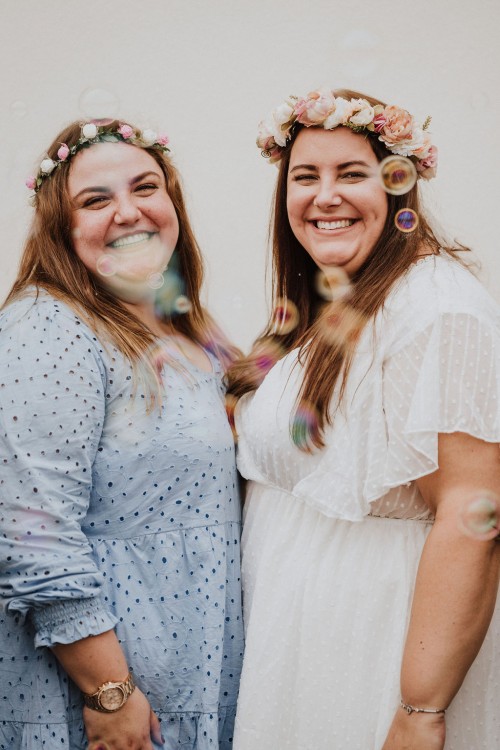 Zwei Frauen schauen lächelnd in die Kamera.