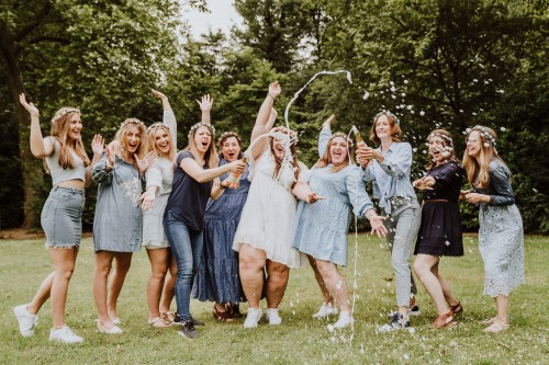 Eine Gruppe von Frauen, die nebeneinander stehen und Sekt versprühen.