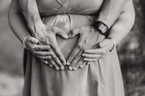 Hände auf einem Schwangerschaftsbauch.