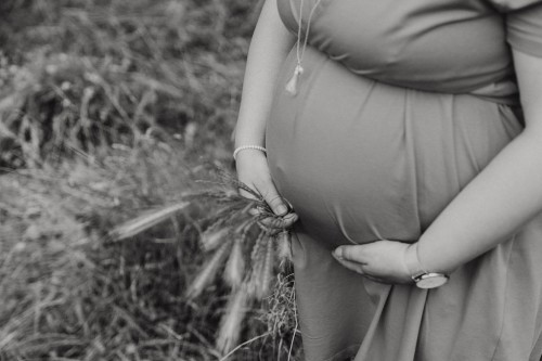 Eine Frau hält ihre Hände auf ihren Bauch.