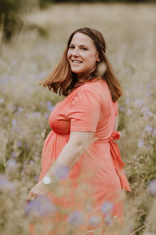 Eine Frau steht mitten in einer Blumenwiese.