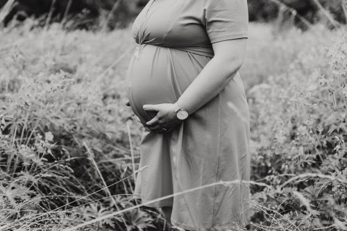 Eine schwangere Frau hält ihre Hände auf ihren Bauch.