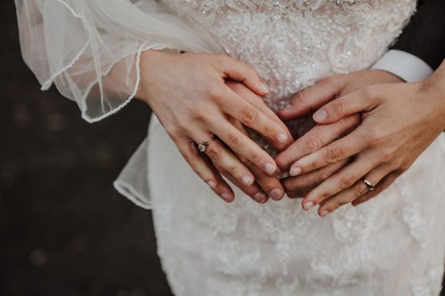 Farbfoto Hochzeitspaar händehaltend übereinander