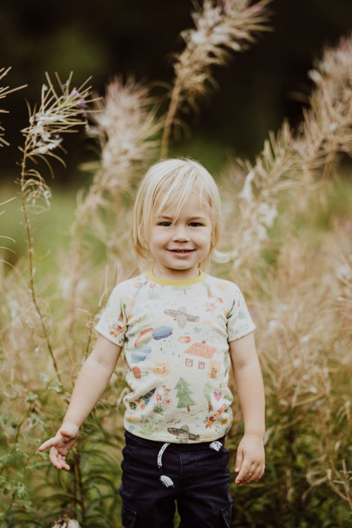 Ein kleines Kind steht auf der Wiese und posiert für ein Foto.