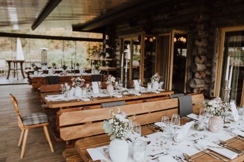 Festlich dekorierte Holztische und Holzbänke.