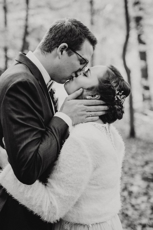 Ein Brautpaar küsst sich im Wald.
