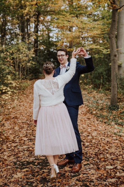 Eine Braut und ein Bräutigam tanzen mitten im Wald.