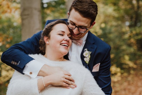 Eine Braut wird von einem Bräutigam umarmt.