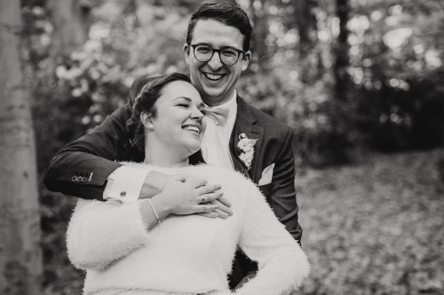 Ein schwarz-weißes Bild von einem Bräutigam wie er eine Braut umarmt.