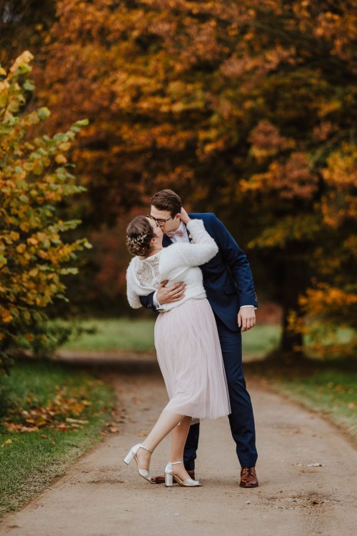 Ein Brautpaar küsst sich mitten im Park.