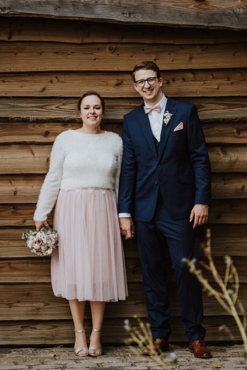 Eine Braut und ein Bräutigam vor einer Holzwand.