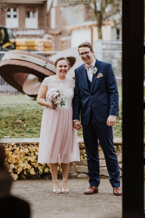 Eine Braut und ein Bräutigam stehen nebeneinander und halten Händchen.