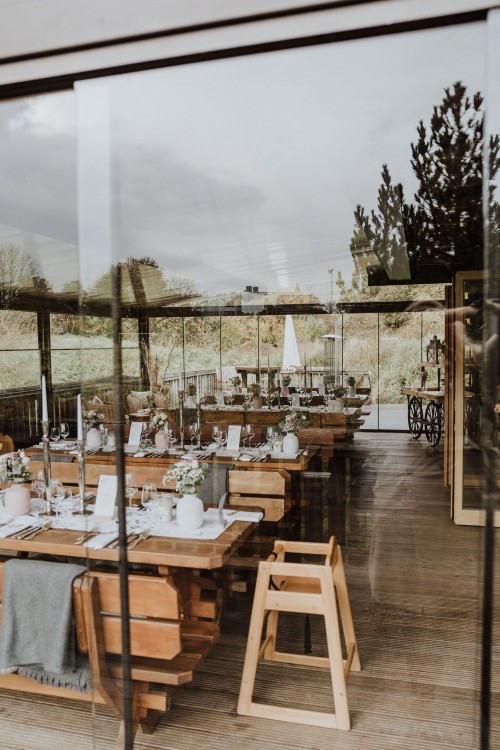 Holztische und Holzbänke im Wintergarten.