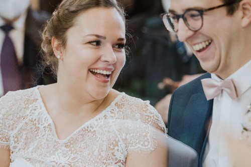 Eine Braut und ein Bräutigam lachen herzlich.