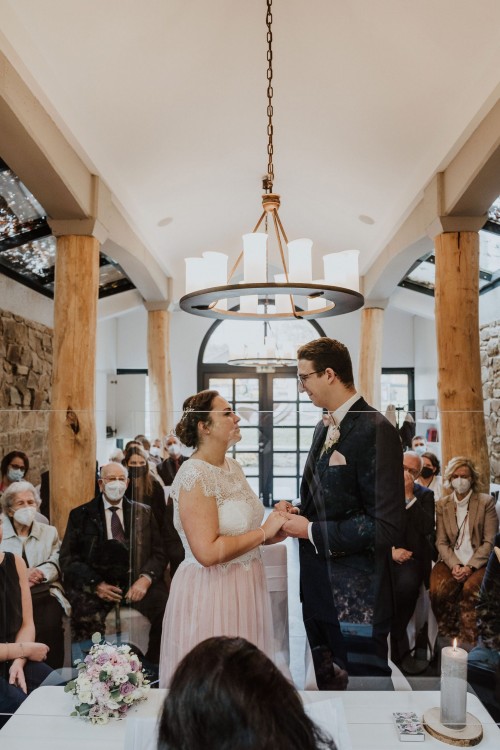 Ein Brautpaar und deren Gäste in einer Kapelle.