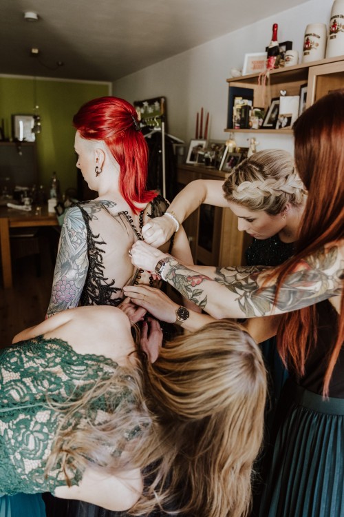 Die Brautjungfern helfen der Braut beim Kleid anziehen.