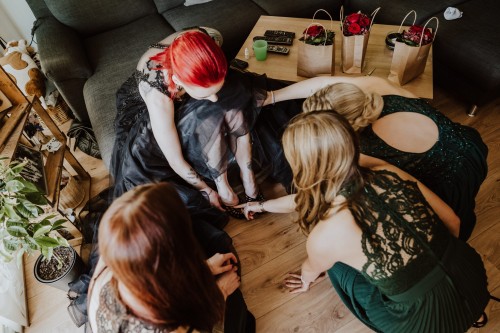 Die Brautjungfern helfen der Braut die Schuhe anzuziehen.