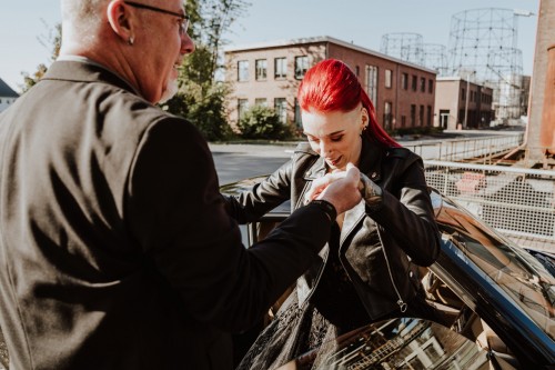 Ein Mann hilft einer Braut aus dem Auto auszusteigen.
