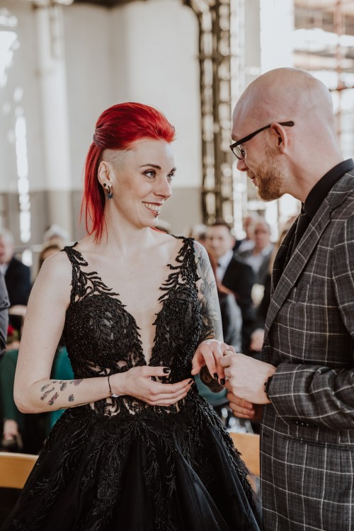 Der Bräutigam steckt der Braut einen Ehering an.