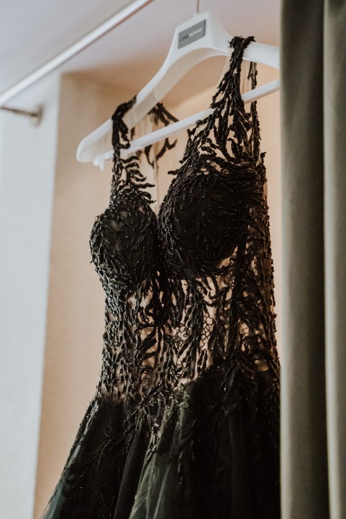 Ein schwarzes Brautkleid hängt auf einer Gardinenstange.
