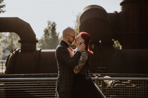 Ein Brautpaar küsst sich vor einer industrieller Kulisse.