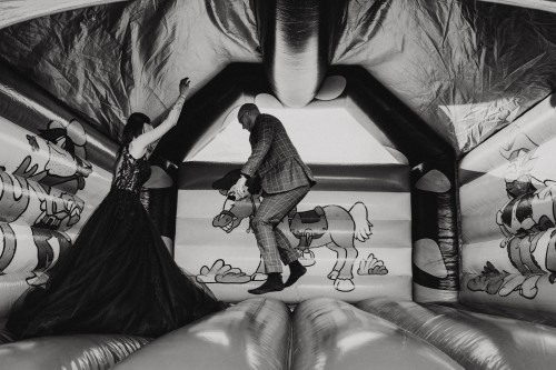 Ein Brautpaar springt in einer Hüpfburg.