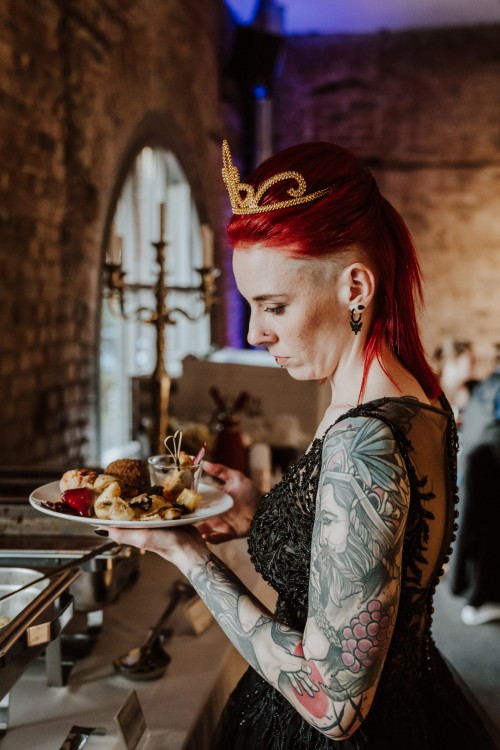 Eine Braut mit Krönchen steht vor dem Buffet.