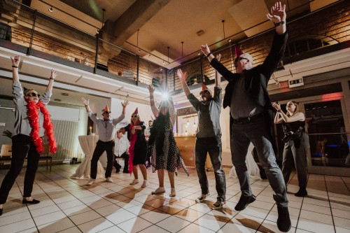 Eine Gruppe von Menschen springen auf der Tanzfläche in die Luft.