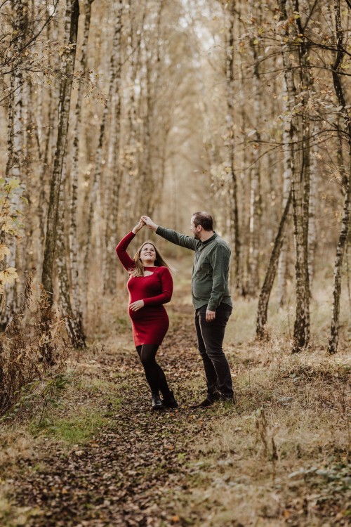 Eine Frau und ein Mann tanzen auf einem Waldweg.