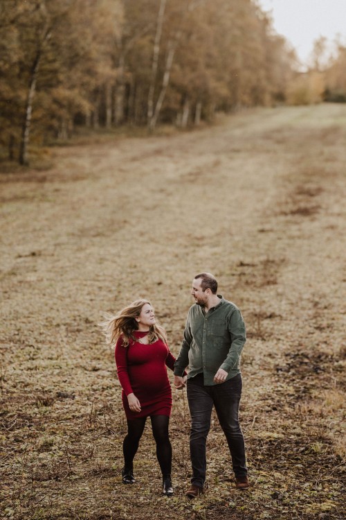 Eine Frau und ein Mann gehen einen Feldweg entlang und halten Händchen.