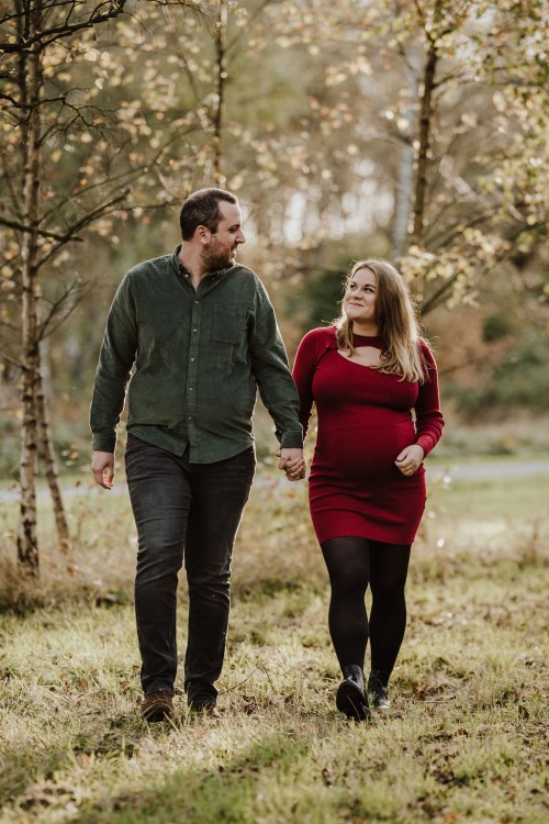 Ein Mann und eine Frau gehen durch einen Wald und halten Händchen.