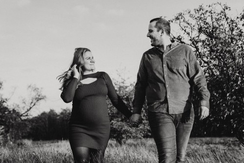Eine Frau und ein Mann gehen durch ein Feld und halten Händchen.