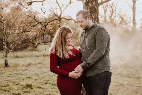 Eine schwangere Frau und ein Mann halten ihre Hände auf dem Babybauch.
