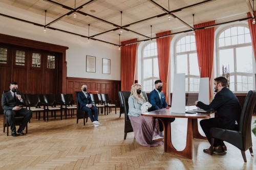 Ein Brautpaar sitzt mit den Trauzeugen im Trausaal vor dem Standesbeamten.